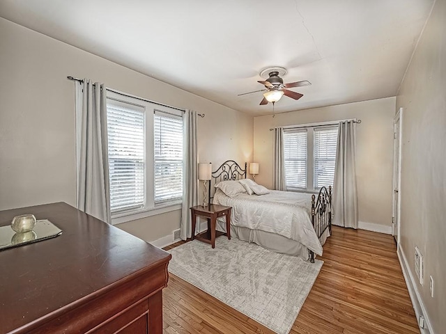 bedroom with a ceiling fan, wood finished floors, and baseboards