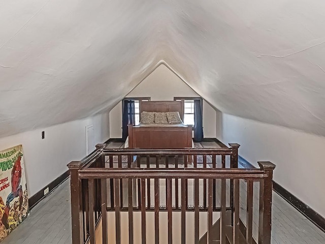 bedroom with vaulted ceiling, hardwood / wood-style flooring, and baseboards