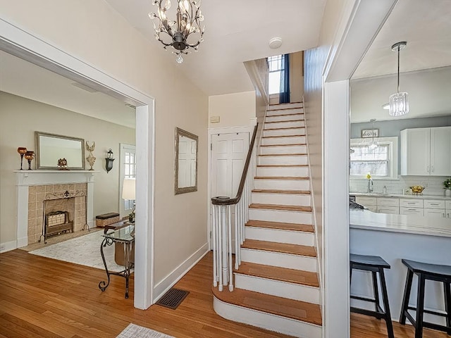 stairway featuring visible vents, baseboards, wood finished floors, and a tile fireplace