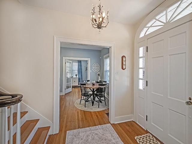 entrance foyer featuring stairway, baseboards, a notable chandelier, and wood finished floors