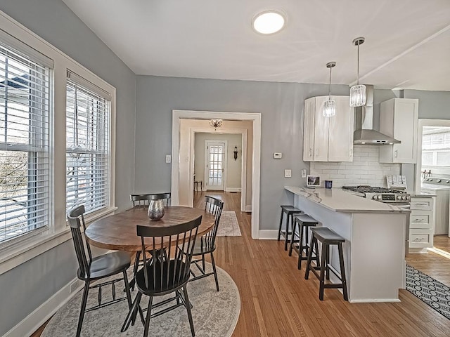 dining room with light wood-type flooring, baseboards, washer / dryer, and a healthy amount of sunlight