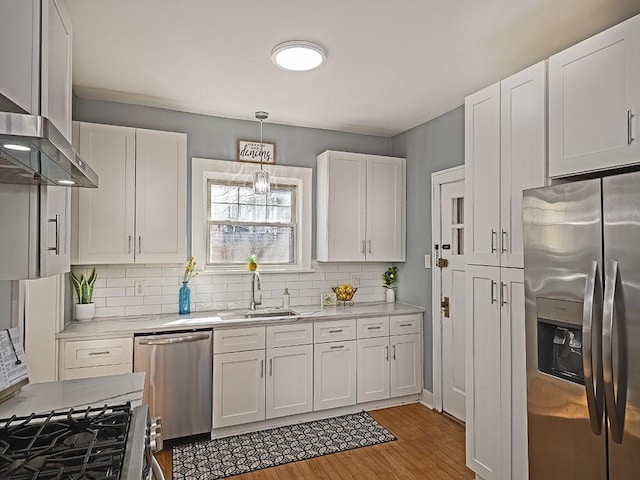 kitchen featuring backsplash, light countertops, white cabinets, stainless steel appliances, and a sink