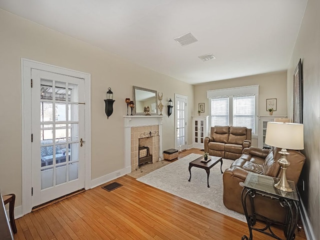 living room with visible vents, a fireplace, baseboards, and hardwood / wood-style flooring