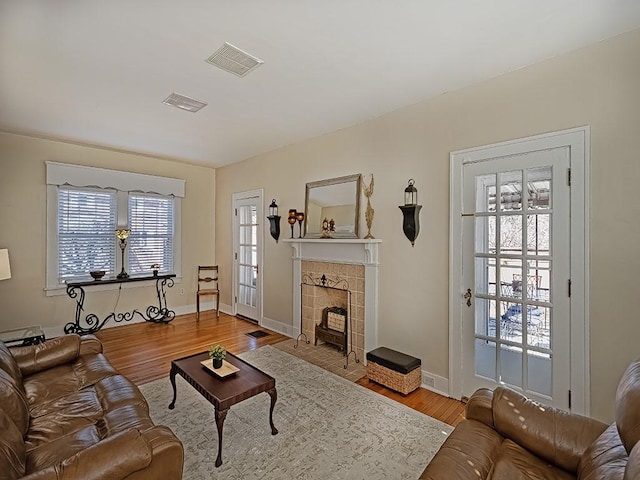 living room with visible vents, baseboards, wood finished floors, and a fireplace