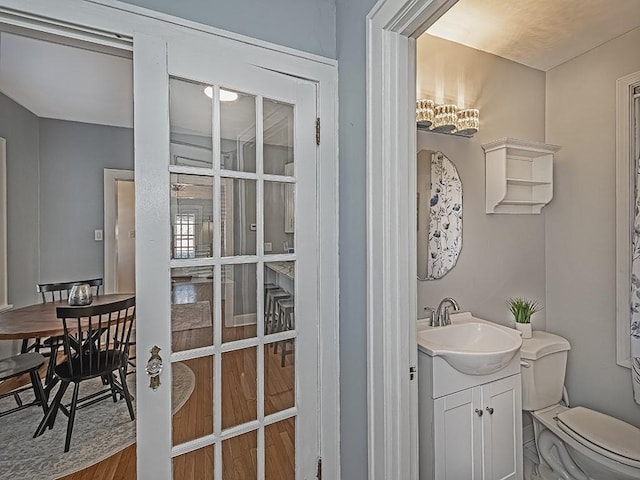 half bathroom featuring vanity, toilet, and wood finished floors