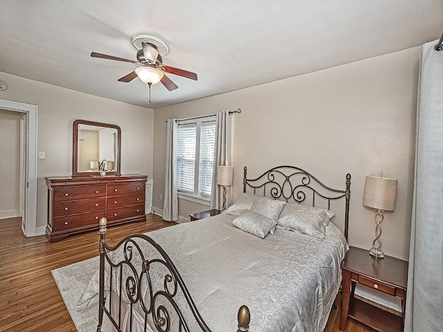 bedroom featuring wood finished floors, baseboards, and ceiling fan