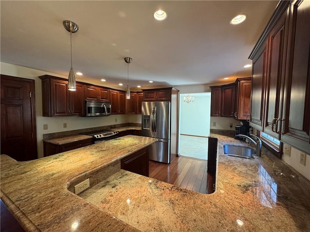 kitchen featuring a sink, light stone countertops, appliances with stainless steel finishes, and recessed lighting