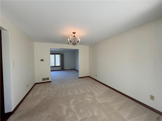 empty room featuring a notable chandelier, visible vents, light carpet, and baseboards