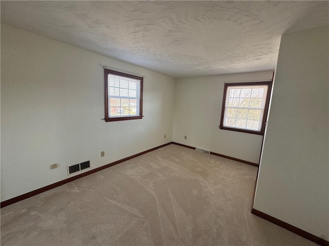 spare room featuring plenty of natural light, baseboards, and visible vents