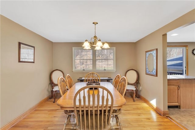 dining room featuring a chandelier, light wood-type flooring, and baseboards