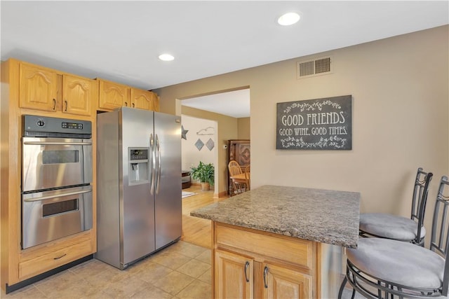 kitchen featuring visible vents, recessed lighting, light brown cabinetry, appliances with stainless steel finishes, and a kitchen bar