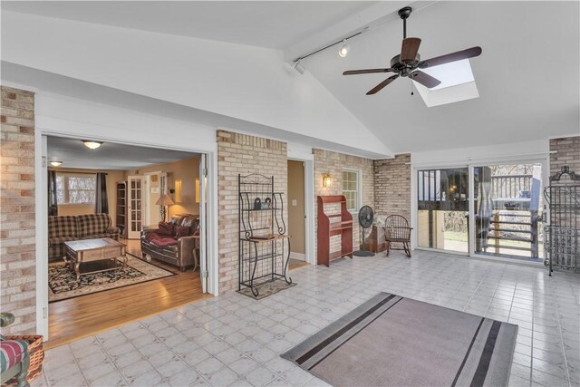 living room featuring tile patterned floors, a ceiling fan, brick wall, and high vaulted ceiling