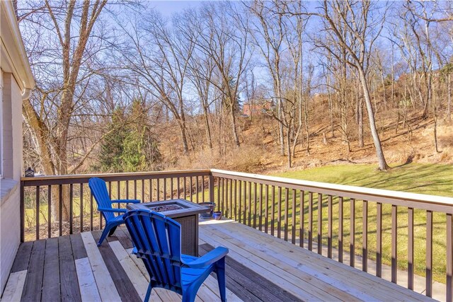 wooden deck with a yard and a fire pit