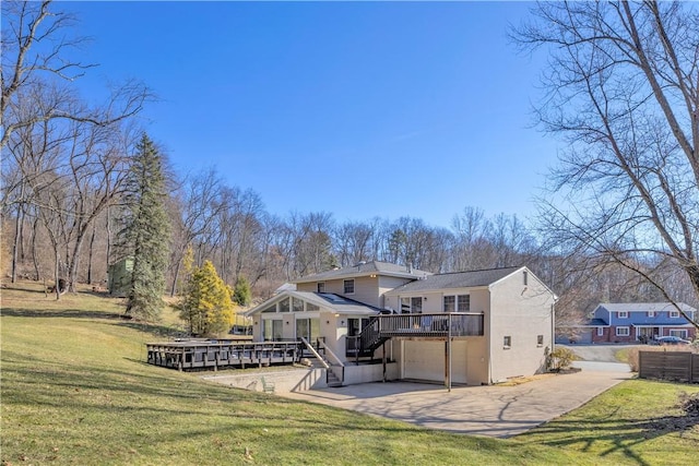 rear view of house featuring driveway, a wooden deck, stairs, a garage, and a lawn