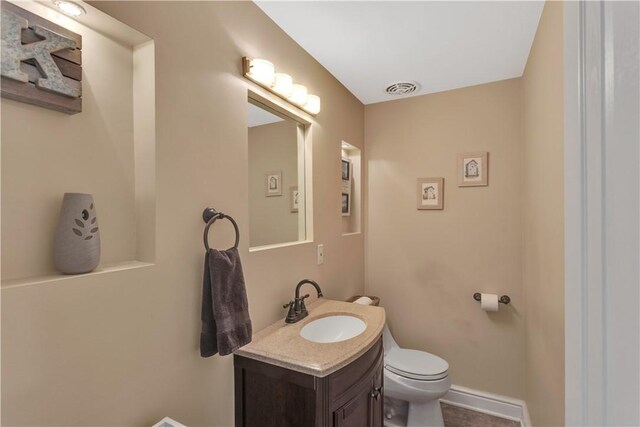 bathroom with visible vents, baseboards, toilet, and vanity