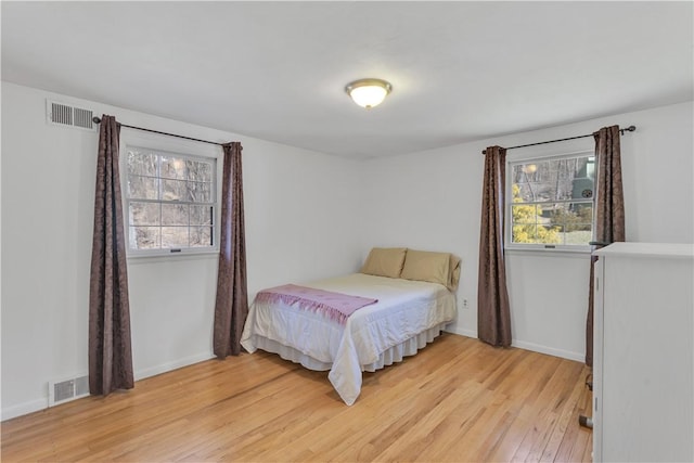 bedroom with visible vents, baseboards, and light wood finished floors