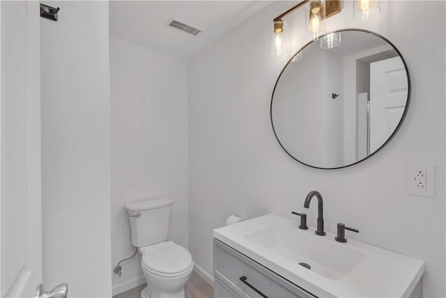 bathroom featuring visible vents, toilet, vanity, and baseboards