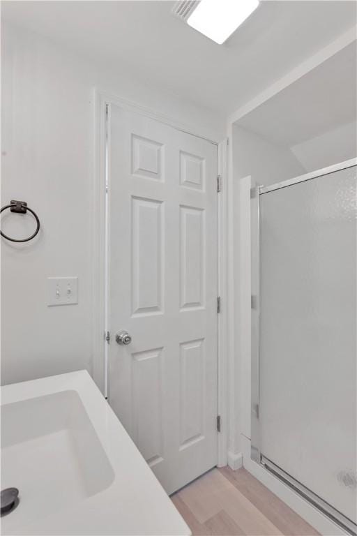 bathroom featuring a shower stall, wood finished floors, and a sink