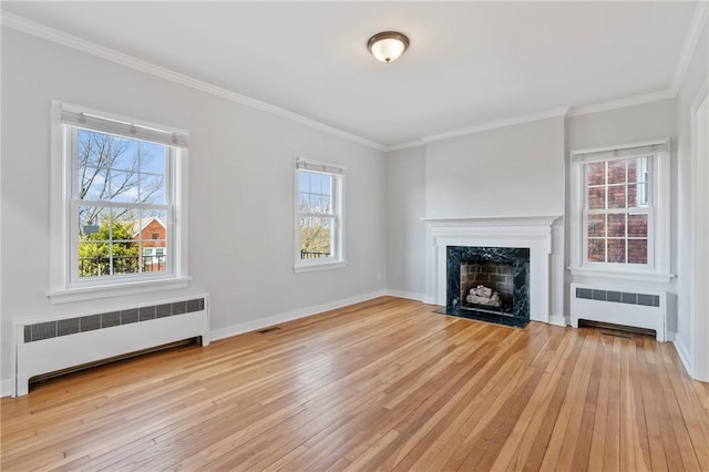 unfurnished living room with light wood finished floors, visible vents, radiator, and a high end fireplace