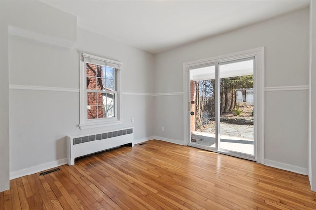 unfurnished room with baseboards, radiator, and light wood-style flooring