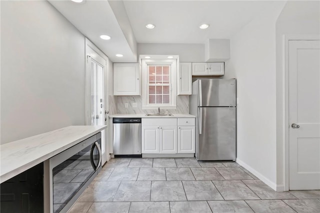 kitchen with white cabinetry, backsplash, appliances with stainless steel finishes, and light countertops