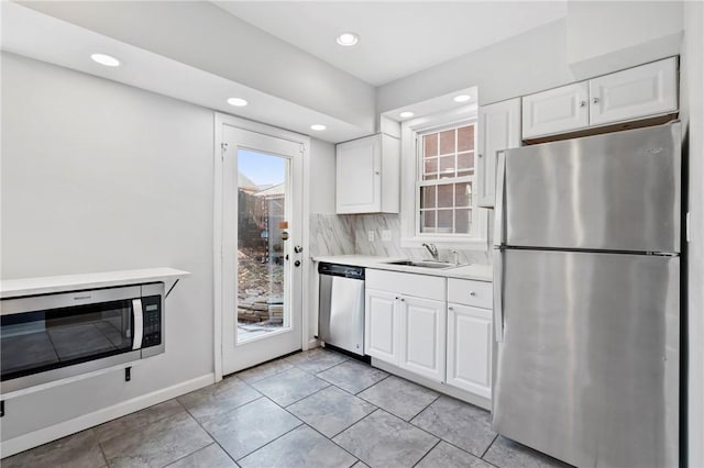 kitchen featuring a sink, stainless steel appliances, white cabinets, light countertops, and decorative backsplash