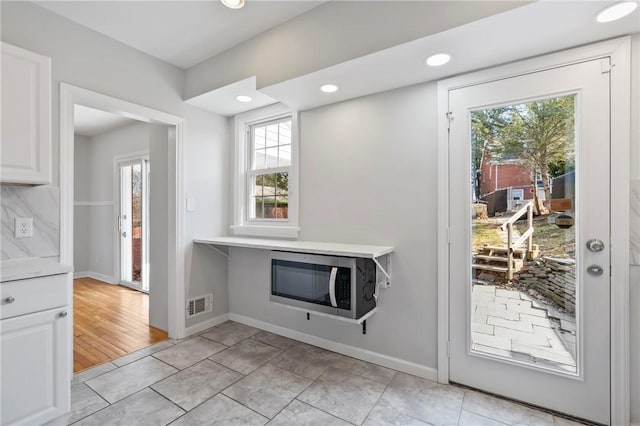 doorway with light tile patterned floors, visible vents, recessed lighting, and baseboards