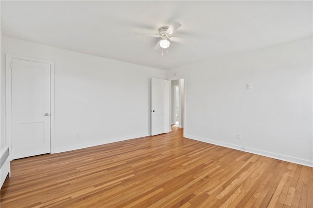 spare room featuring light wood-type flooring, baseboards, and a ceiling fan