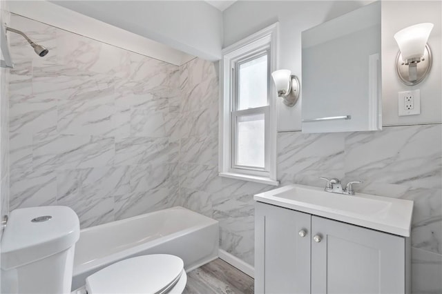 full bathroom featuring toilet, wood finished floors, tile walls, shower / bath combination, and vanity