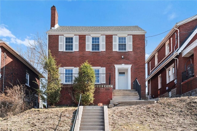 colonial house featuring brick siding and a chimney