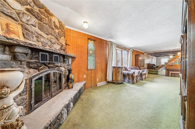 carpeted living area featuring visible vents, a textured ceiling, stairway, wood walls, and a fireplace