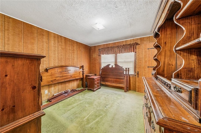 bedroom with light carpet, wood walls, and a textured ceiling