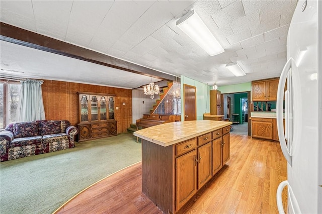 kitchen featuring brown cabinetry, open floor plan, a kitchen island, and freestanding refrigerator