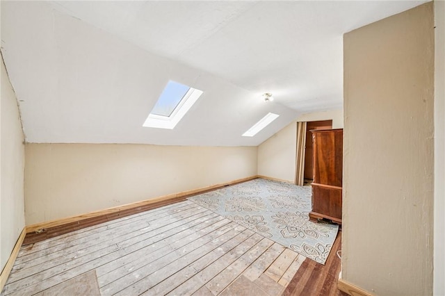 additional living space with baseboards, lofted ceiling, and wood-type flooring