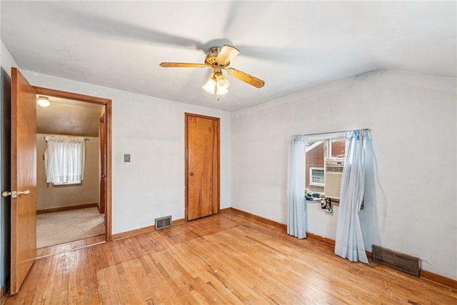 unfurnished bedroom with visible vents, baseboards, light wood-type flooring, and lofted ceiling