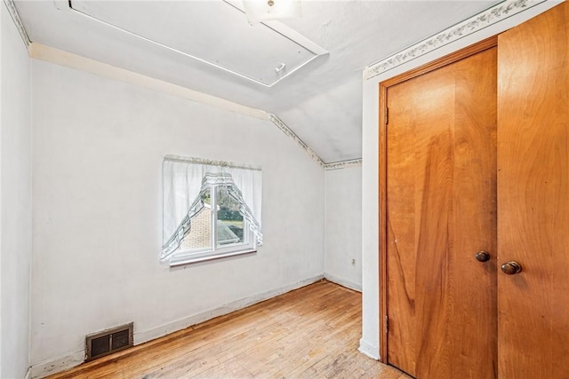 interior space featuring visible vents, hardwood / wood-style floors, baseboards, attic access, and vaulted ceiling