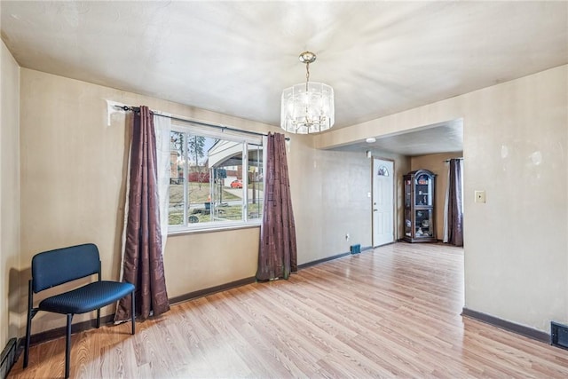 empty room with light wood-type flooring, baseboards, and a chandelier