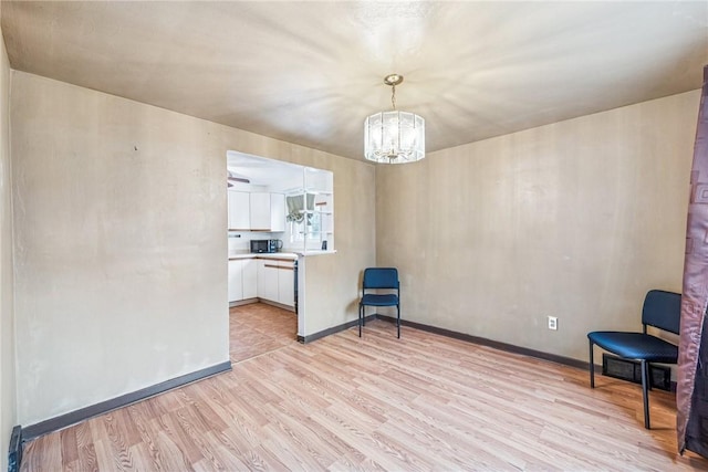 interior space with baseboards, light wood-type flooring, and an inviting chandelier