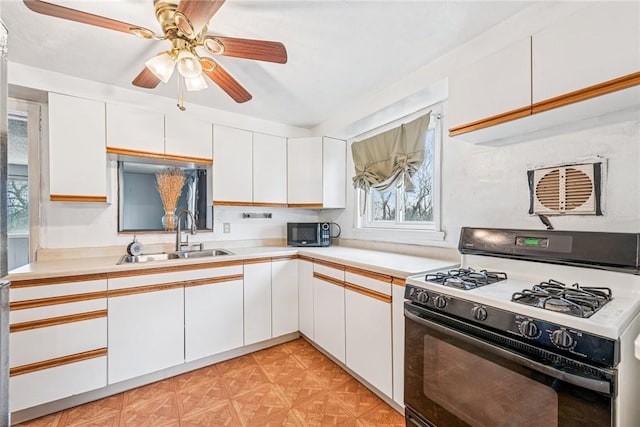 kitchen with a sink, stainless steel microwave, gas stove, white cabinets, and light countertops