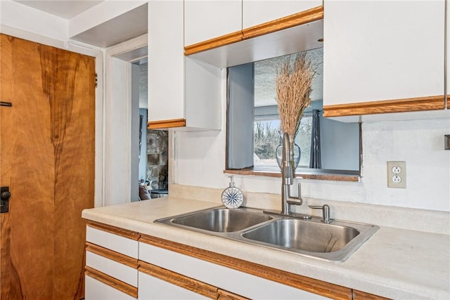 kitchen with light countertops, white cabinets, and a sink