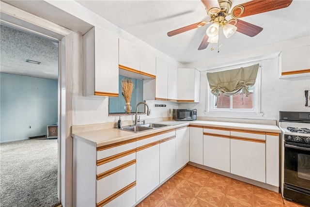 kitchen with a sink, a textured ceiling, white cabinetry, gas range, and stainless steel microwave