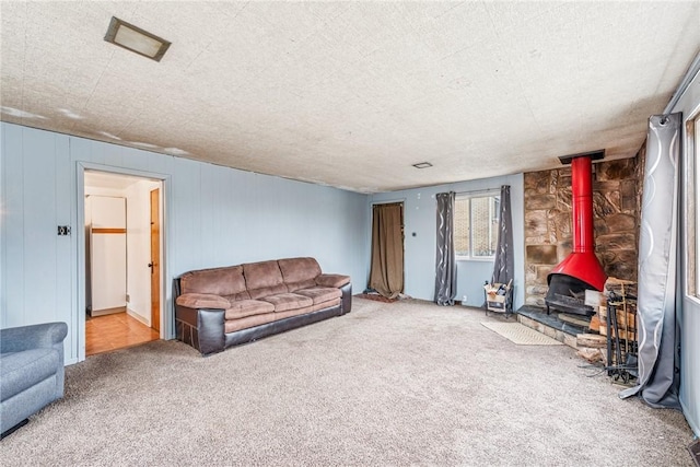 carpeted living area featuring a wood stove and a textured ceiling