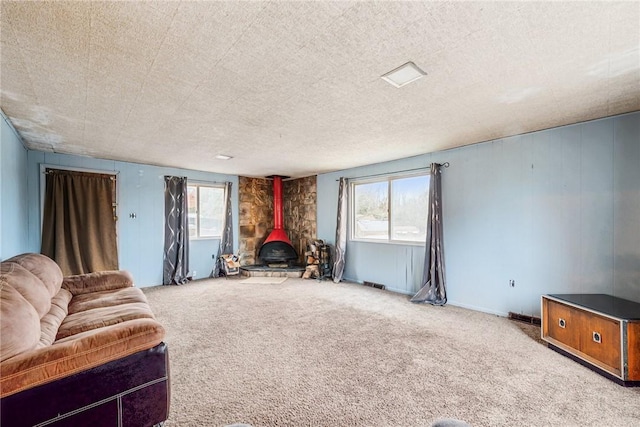 living area with carpet flooring, a textured ceiling, and a wood stove