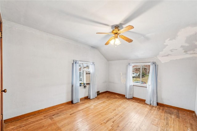 interior space featuring baseboards, light wood-style flooring, and vaulted ceiling