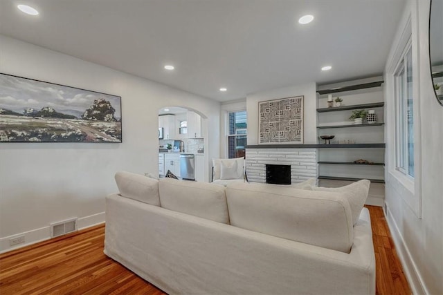 living area featuring recessed lighting, wood finished floors, visible vents, and arched walkways