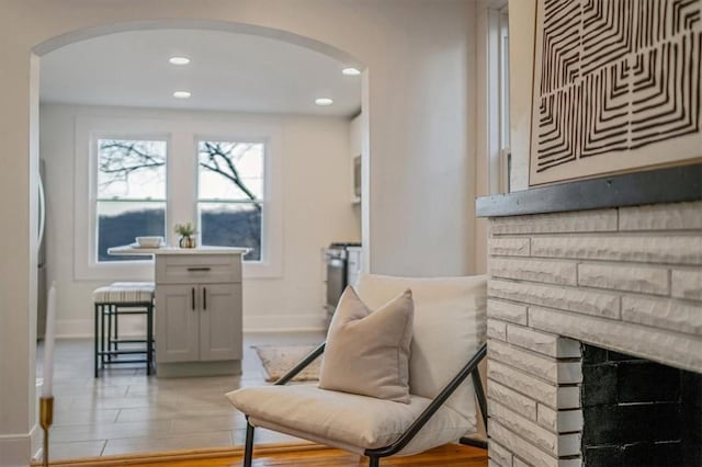 sitting room with recessed lighting, a fireplace, arched walkways, and baseboards