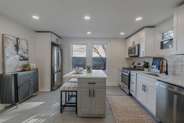 kitchen featuring a kitchen island, a sink, stainless steel appliances, a kitchen bar, and tasteful backsplash