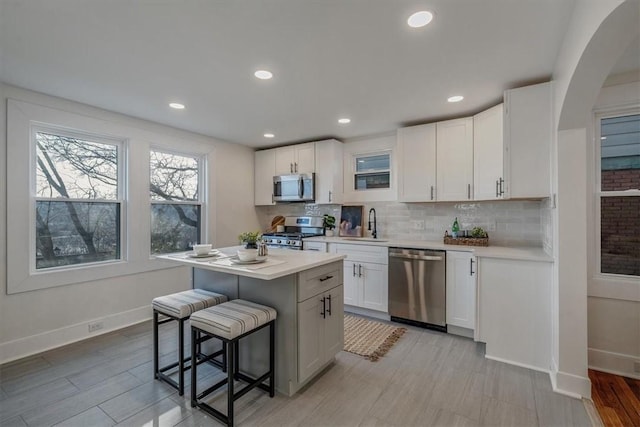 kitchen with stainless steel appliances, a kitchen breakfast bar, tasteful backsplash, and light countertops