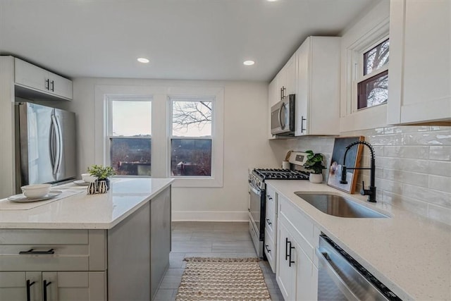 kitchen with light stone countertops, a wealth of natural light, decorative backsplash, stainless steel appliances, and a sink