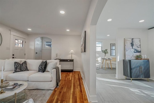 living room with recessed lighting, baseboards, arched walkways, and light wood-style flooring